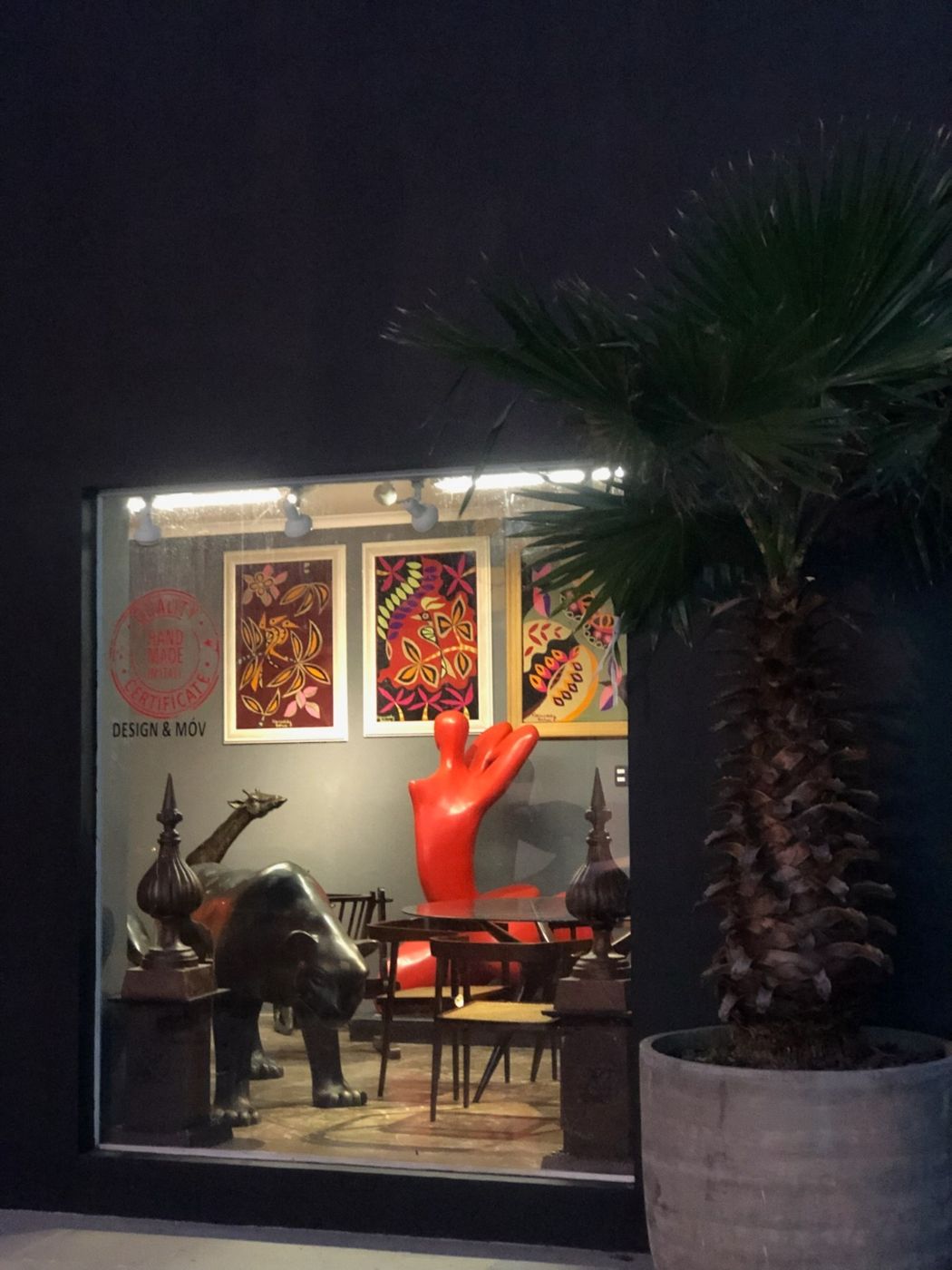 Vitrine com quadros coloridos, escultura vermelha e animais em bronze
